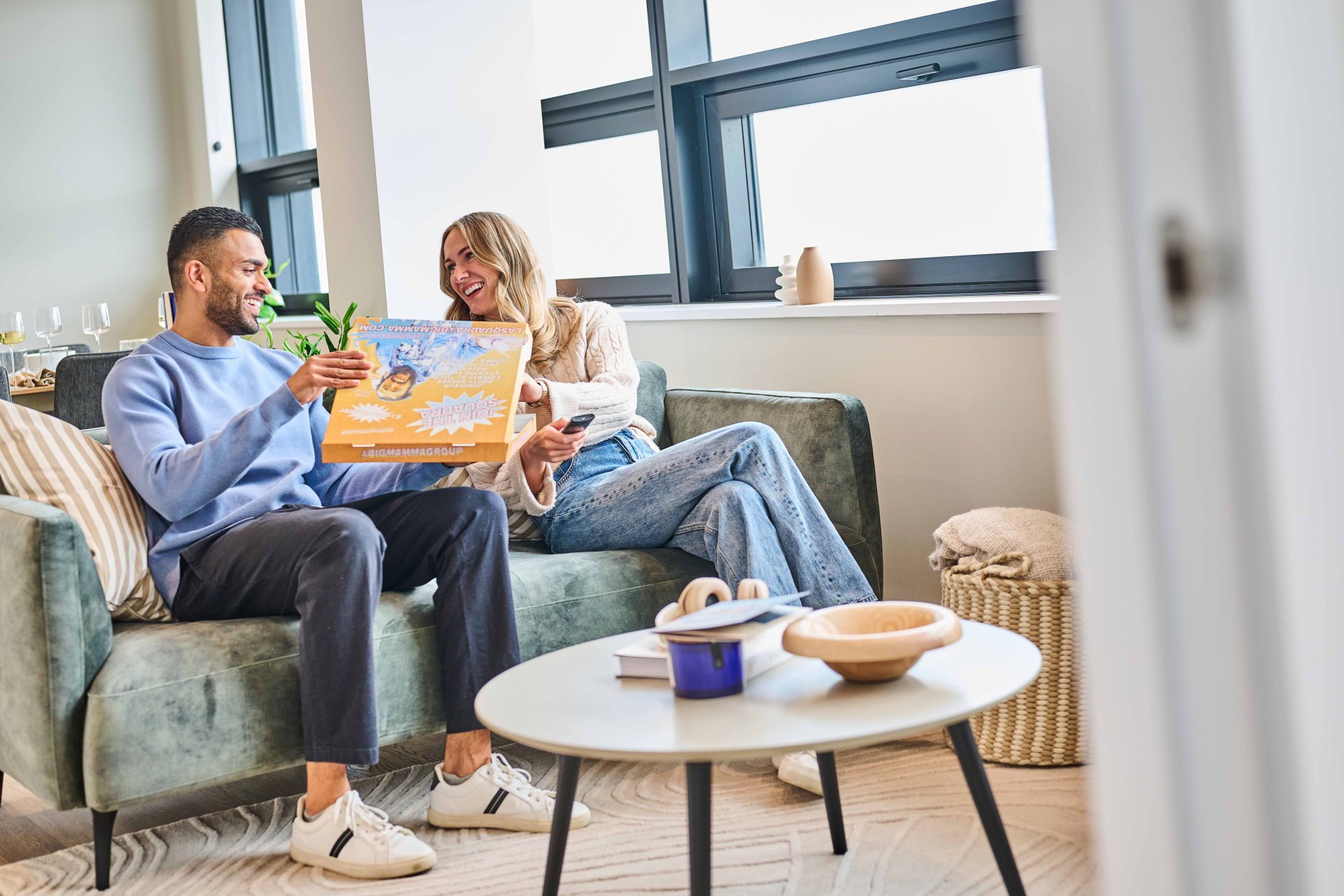 Couple relaxing on a sofa with takeaway pizza in The Octagon luxury residential apartment