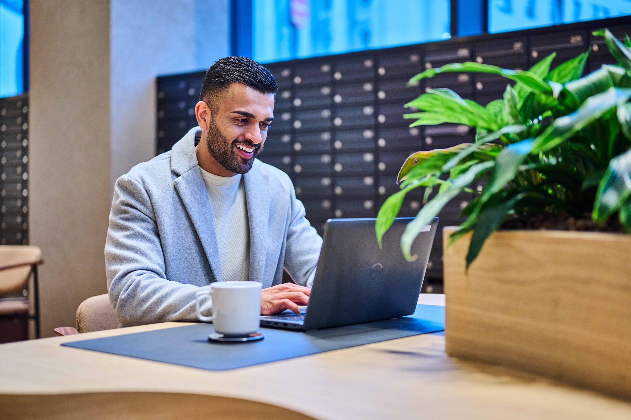 Male resident using laptop in The Octagon lounge, showcasing comfortable living spaces in Birmingham city centre luxury apartments