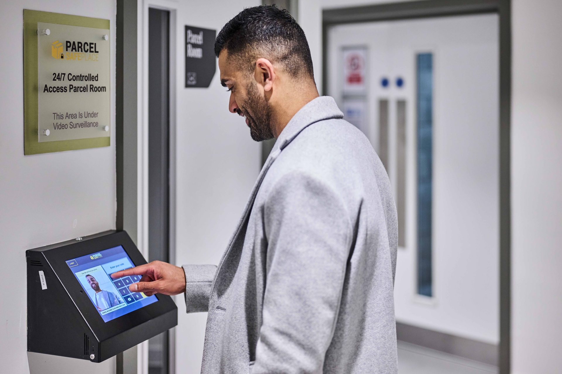 Male resident using secure access screen at The Octagon parcel room, showcasing smart delivery amenities in Birmingham luxury apartments